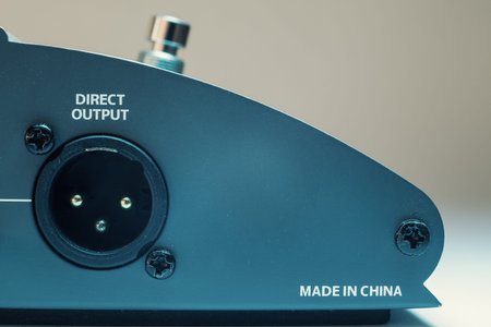 Conceptual composition about manufacturing in China, part of a guitar pedal, closeup view on output...