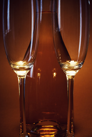 Two empty glasses and a bottle of spirit drink on brown background.の写真素材