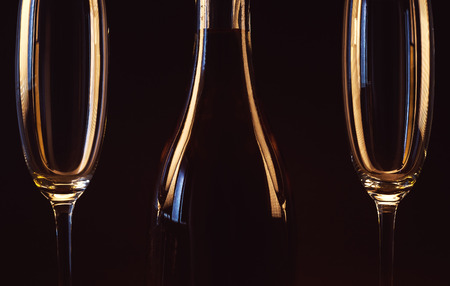 Two empty glasses and a bottle of spirit drink on brown background.の写真素材