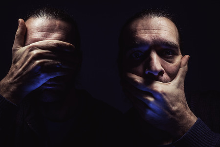 Portrait of a man with hands on eyes and mouth, conceptual composition about freedom and human rights.の写真素材