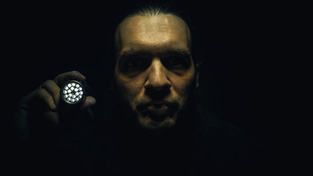Man holding a lamp and looking to something in front of him.