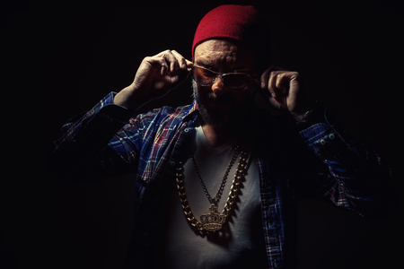 Portrait of a middle aged man wearing red hat and big golden jewelry, with strong glance through sun glasses.の写真素材