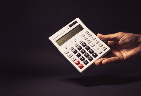 Conceptual composition, man's hand holding an old electronic calculator with zero on it.の写真素材