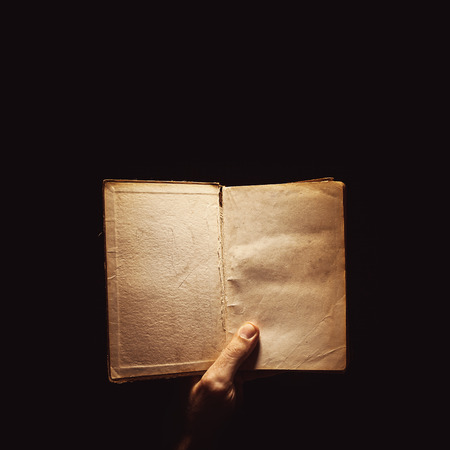 Conceptual composition about reading books, a male hand holding a book in the dark.の写真素材