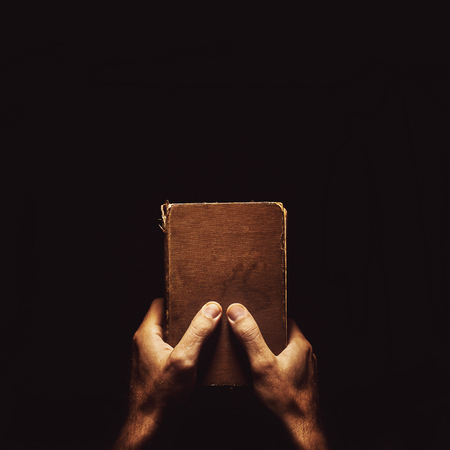 Conceptual composition about reading books, a male hand holding a book in the dark.の写真素材