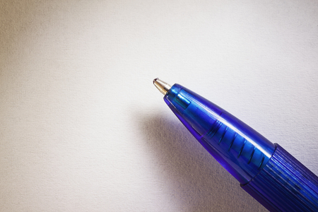Closeup view of a blue ball pen on white paper.の写真素材