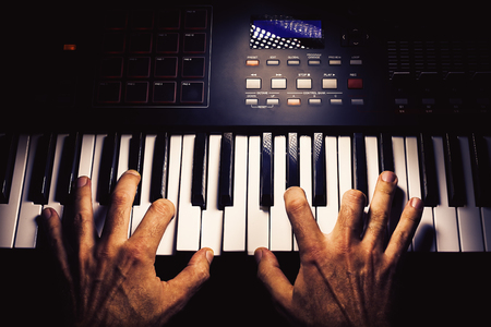 Details of a modern midi keyboard with male hands playing on it.の写真素材