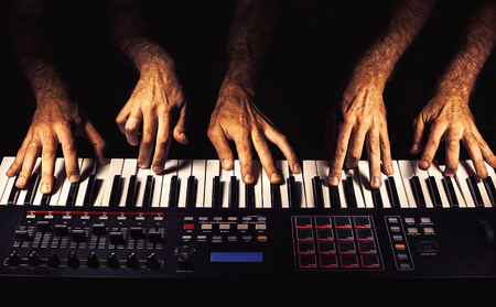 Details of a modern midi keyboard with male hands playing on it.の写真素材