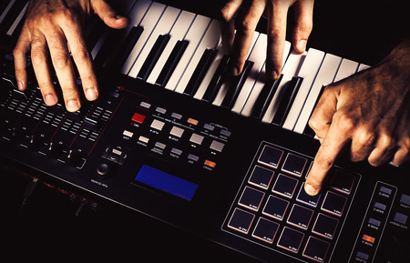 Details of a modern midi keyboard with male hands playing on it.の写真素材