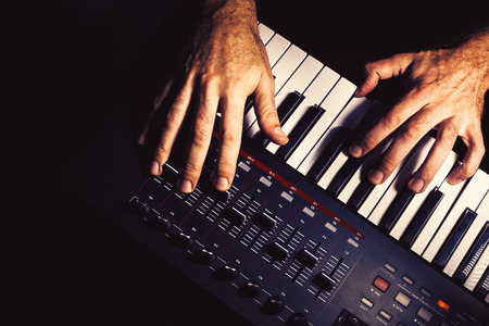 Details of a modern midi keyboard with male hands playing on it.の写真素材