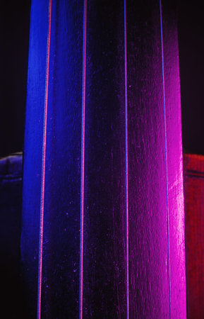 Studio composition of an old dusty violin, blue and purple illumination from aside, closeup view on neck and strings.の写真素材