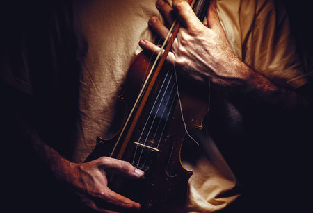 Man is holding an old violin, closeup view on body.の写真素材
