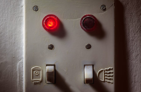 Details of an old dirty plastic switches for bathroom, red light is on for boiler.