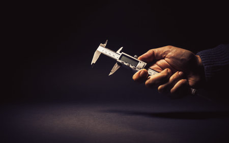 Vernier caliper in male hand, conceptual composition about precise measuring.