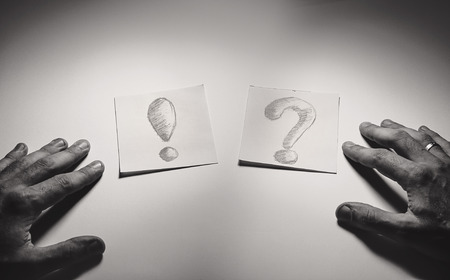 Exclamation and question signs drawn on paper, male hands in front. の写真素材