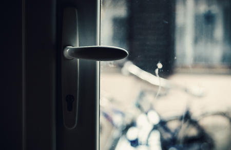 Closeup view of modern door handle, bicycle and a window of a house in blurry background. 
の写真素材