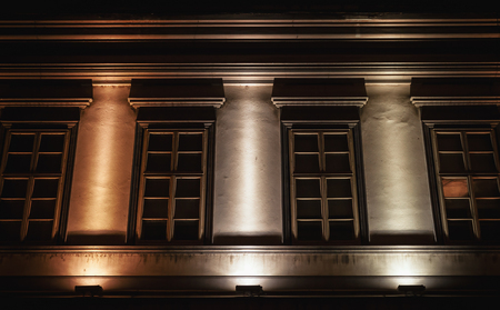 Details of an old museum like buildings, decorative windows and stubs, during night.の写真素材