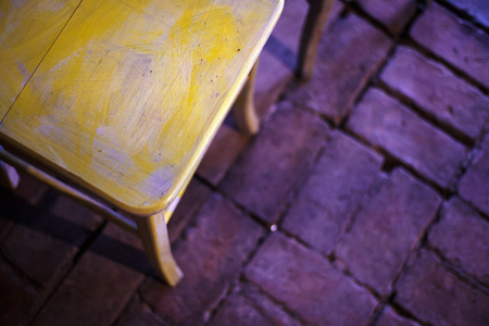 Details of a colorful old wooden chair, brick floor in background.の写真素材
