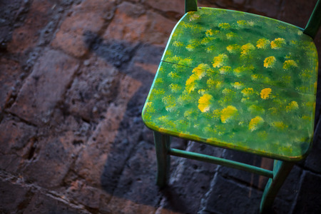 Details of a colorful old wooden chair, brick floor in background.の写真素材
