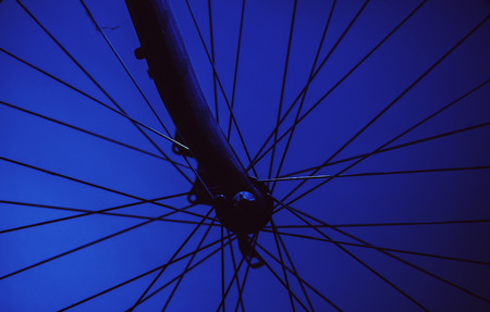 Closeup view of bicycle wheel, dark background and strong highlights.の写真素材