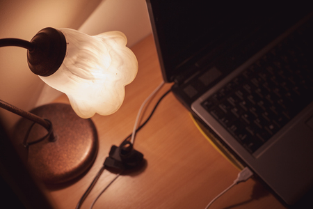 Details of a working table, closeup view of decorative lamp and part of laptop.の写真素材