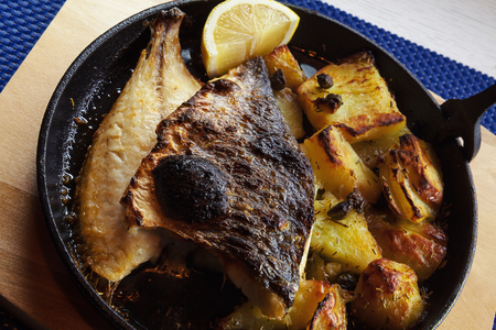 Piece of fried fish and potatoes in pan.の写真素材