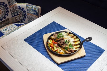 Delicious portion of meat with potatoes and fresh salad in hot frying pan.の写真素材