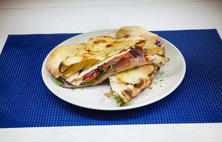 Sandwich with ham, tomato, onion and green salad in white plate.の写真素材
