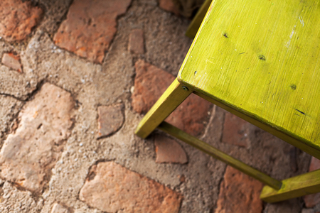 Part of a green wooden chair on old brick floor.の写真素材