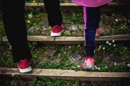 View from back on mother's and daughter's legs on stairs.の写真素材