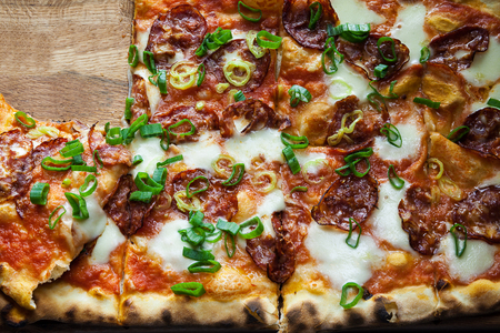 Tasty hot pizza with sausages and fresh pepper on wooden plate.の写真素材