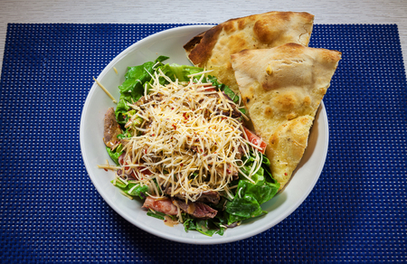 Pieces of meat with pasta and green salad in white plate.の写真素材