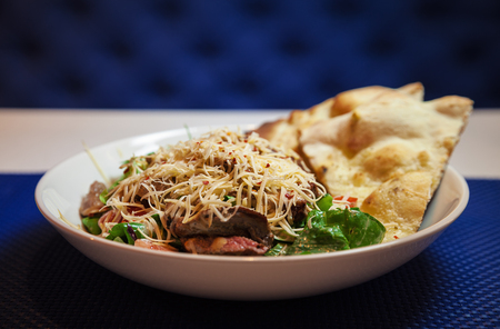 Pieces of meat with pasta and green salad in white plate.の写真素材