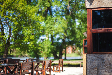 Details of a restaurant in town park, closeup of architecture, wooden benches and tables in blurry background.の写真素材
