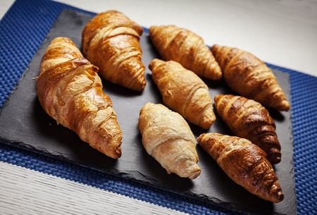 Various butter croissant on black ceramic plate.の写真素材