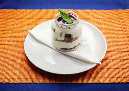 Cheese cake in glass jar on white plate with handkerchief. の写真素材