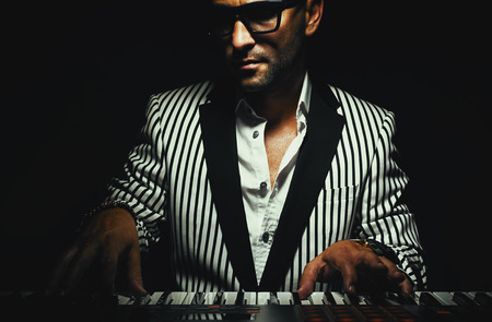 Musician on his instrument, keyboard player in stripped jacket, playing synth.の写真素材