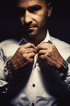 Adult man gets dressed, wearing interesting bracelets and old digital watch.の写真素材