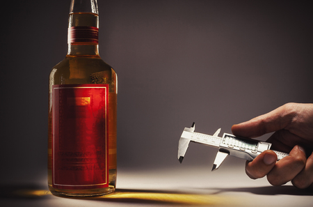 Alcohol drink in a bottle and hand with micro measure tool. の写真素材