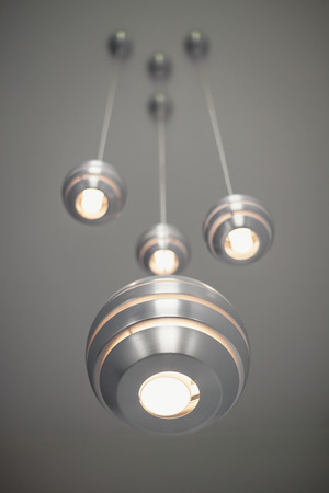 Details of a modern decorative lights, metal balls hanged on high gray ceiling.の写真素材