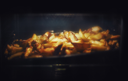 Details of baked potatoes in oven, closeup view through glass.の写真素材