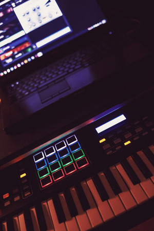 Details of a modern midi keyboard and laptop in blurry background.の写真素材