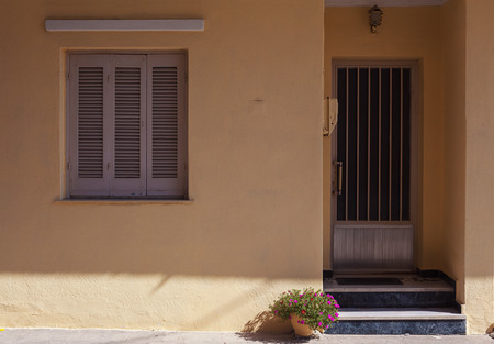 Old house entrance and window, decorative purple flowers in vase in front of. の写真素材