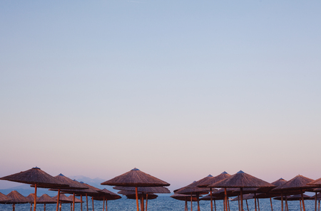 Details of Greek beaches, top of wooden reed sun-umbrellas during sunset or sunrise.の写真素材