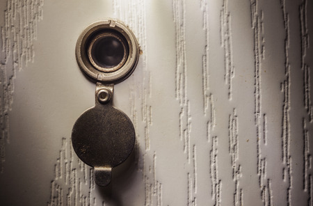 Closeup view on details of an old peephole in white wooden doors.の写真素材