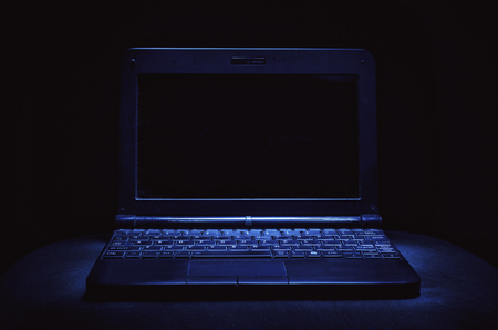Closeup view on old dusty and dirty laptop in the dark.の写真素材