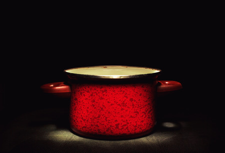 One old red cooking pot in the dark, accentuated shape and texture. の写真素材