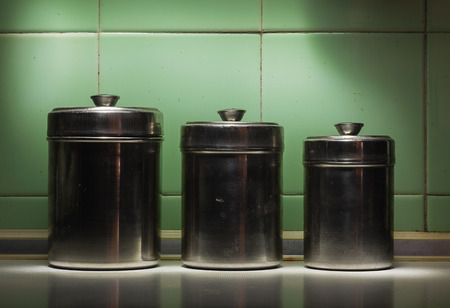 Closeup view of three old and dirty metal bowls in front of tiled green wall.の写真素材