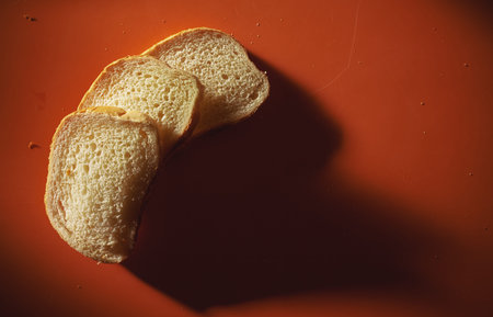 Three pieces of white wheat bread on orange table. 
