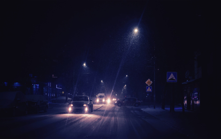 Snow has fallen in the city, a difficult situation on the street, the cars slowly pass with great caution, the night scene.の写真素材